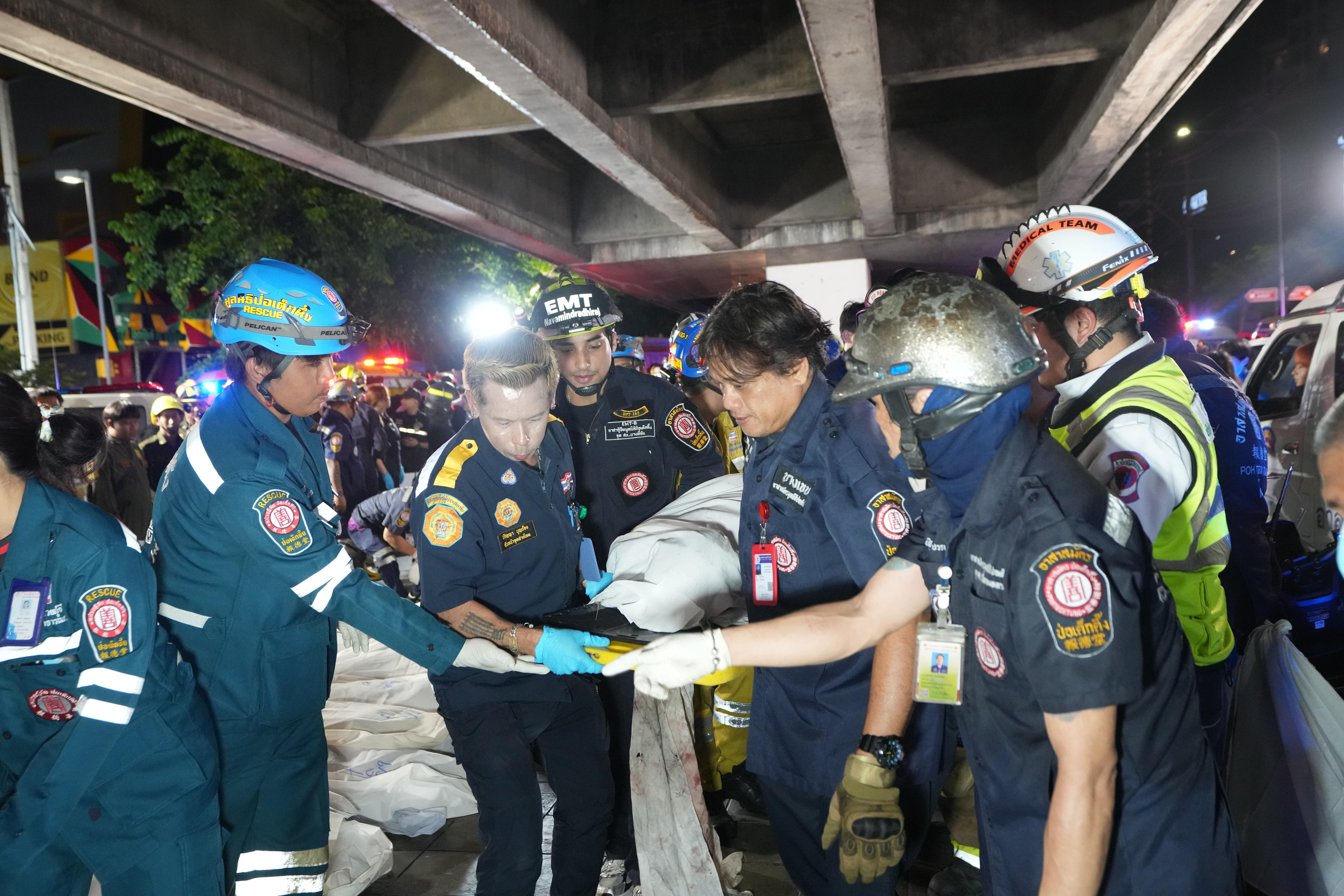 Rescuers carrying a body covered by a white sheet.