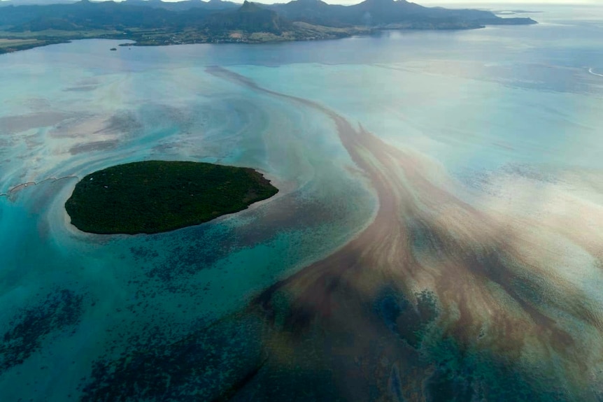 An oil slick expands across a body of sea water near an island off the coast of Mauritius