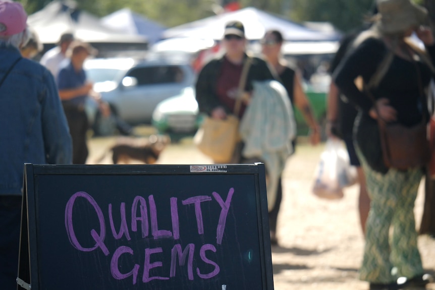 A sign that says 'Quality Gems', people blurred out in the background.