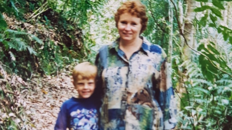Julie, mother and her young son, James standing on a path surrounded by green trees