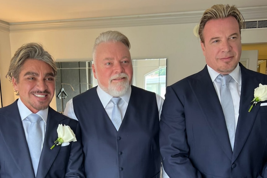 three men wearing suits looking at the camera