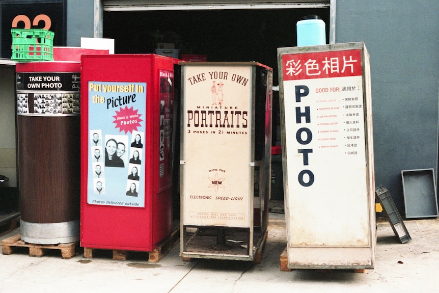 A series of four different vintage photobooths lined up alongside each other at a warehouse.