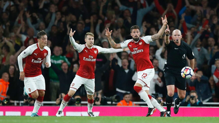 Olivier Giroud and Arsenal teammates raise their arms as Mike Dean whistles for a goal.