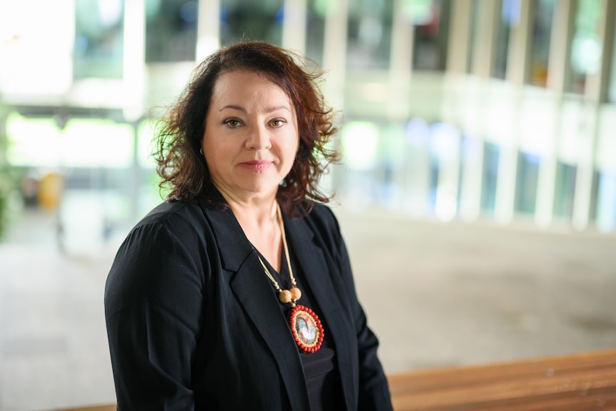 A professional woman in a suit looking pensive with a legal businesslike backdrop.