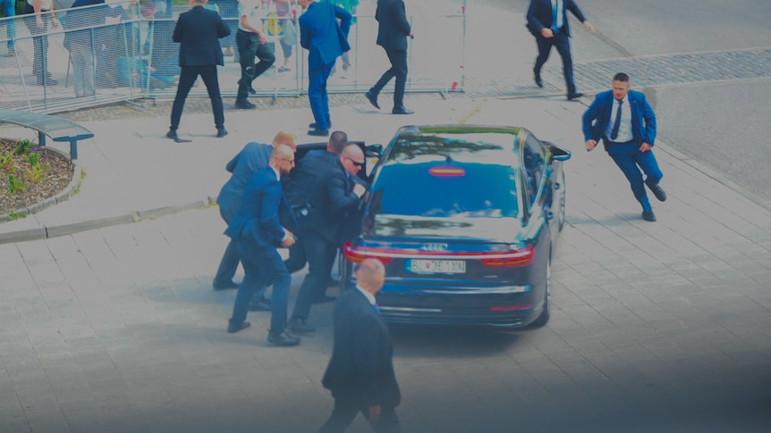 A group of men in suits getting into a car.