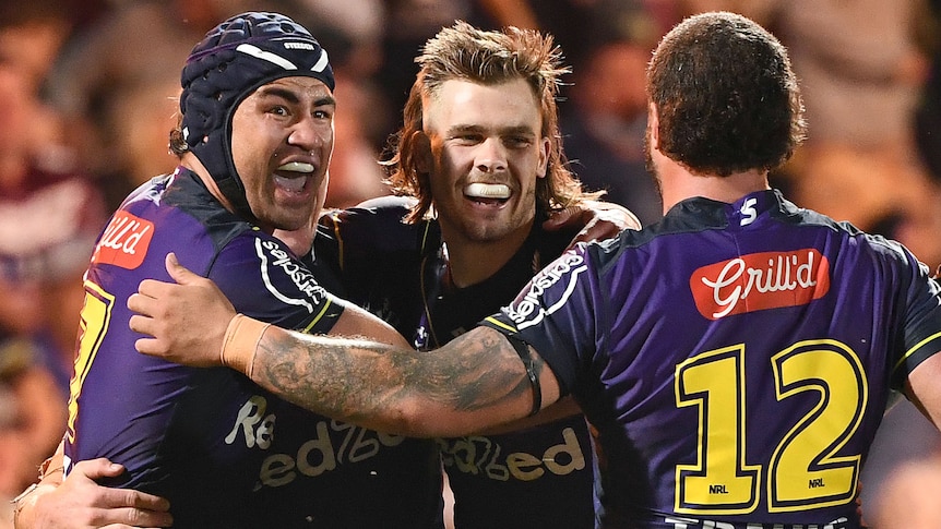 Three rugby league player celebrate after a try was scored during a match