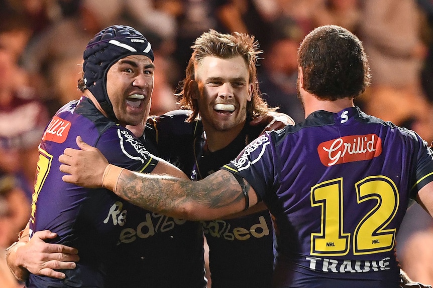 Three rugby league player celebrate after a try was scored during a match