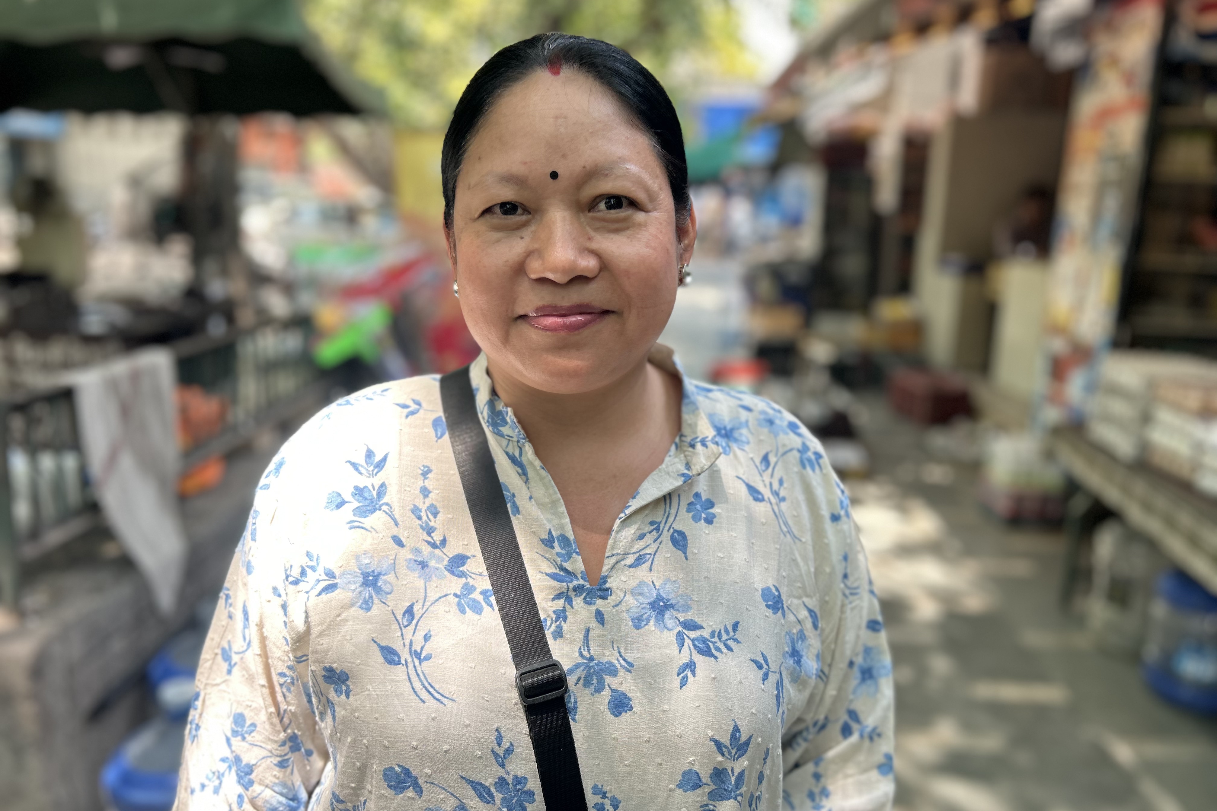 Woman wearing a blue and white kurta and a bag on her shoulder.