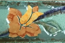 A ceramic tile with a yellow flower design on it.