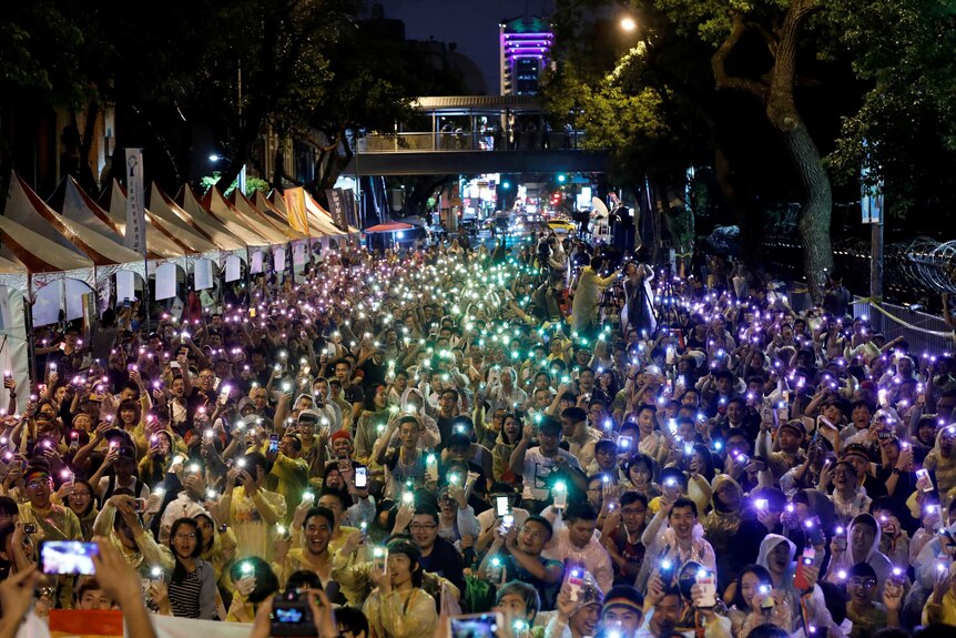 Supporters wave their mobile phone torches in the colours of the rainbow.