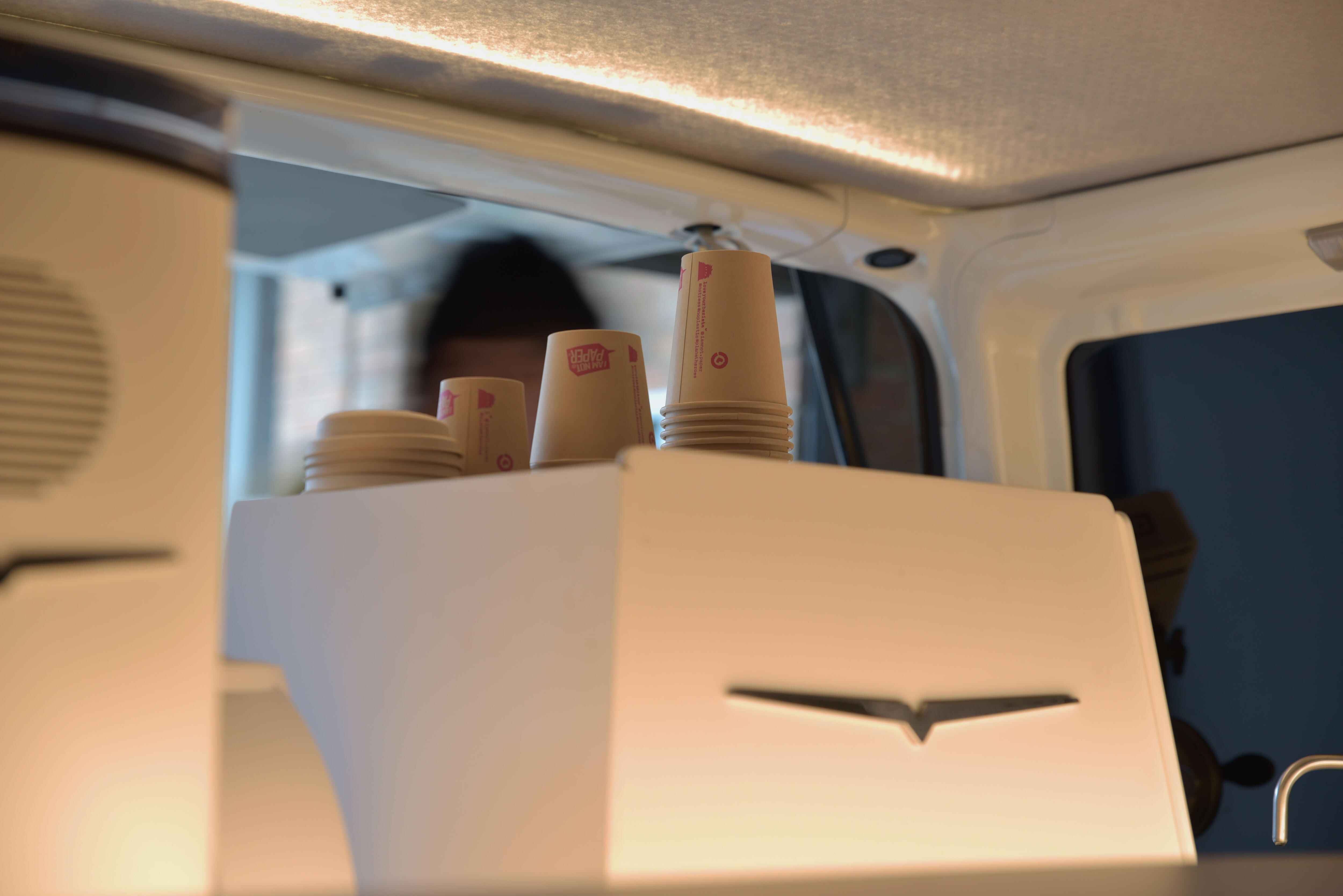 Paper coffee cups stacked on top of a coffee machine.