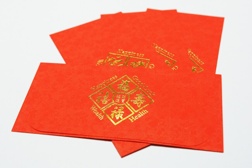 Red envelopes have Chinese characters and read 'wealth, health, happiness, good luck'