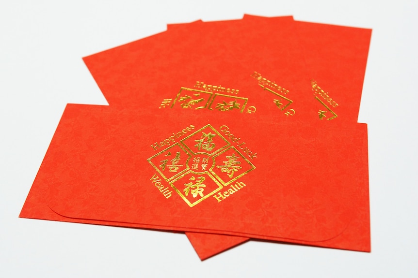 Red envelopes have Chinese characters and read 'wealth, health, happiness, good luck'