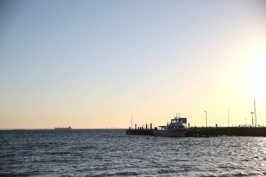 A wide shot of the ocean viewed from the Esperance foreshore with a Water Police vessel moored at a jetty.