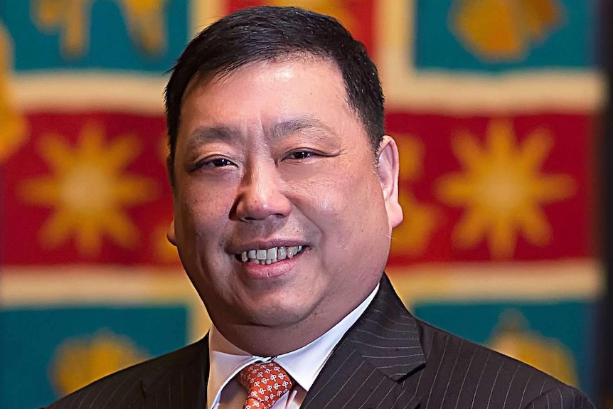 Ernest Wong stands in front of a colourful backdrop.