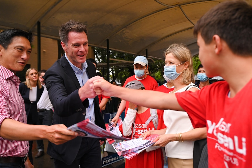 A man in a suit shaking a child's hand.