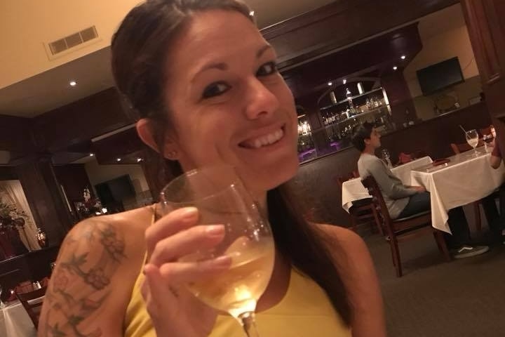 Hannah Ahlers smiles with a glass of wine in hand