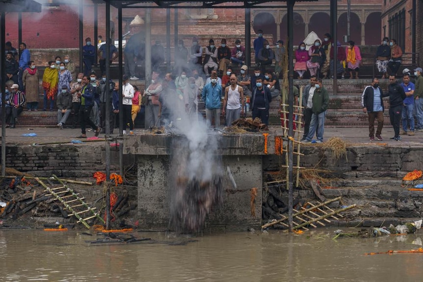 A man pushes cremated remains into the Bagmati River 