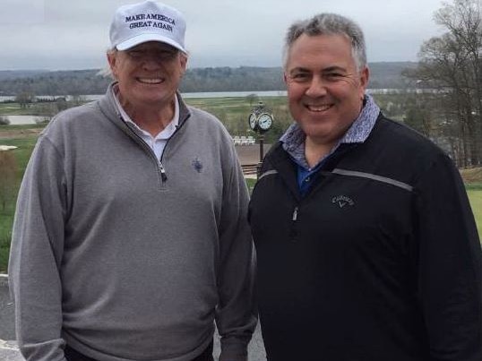 Two men, one wearing a white cap and one with salt-and-pepper hair - stand next to each other grinning at the camera