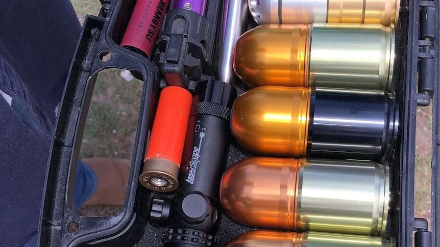 A range of ammunition in a black case being held by a gloved police officer.