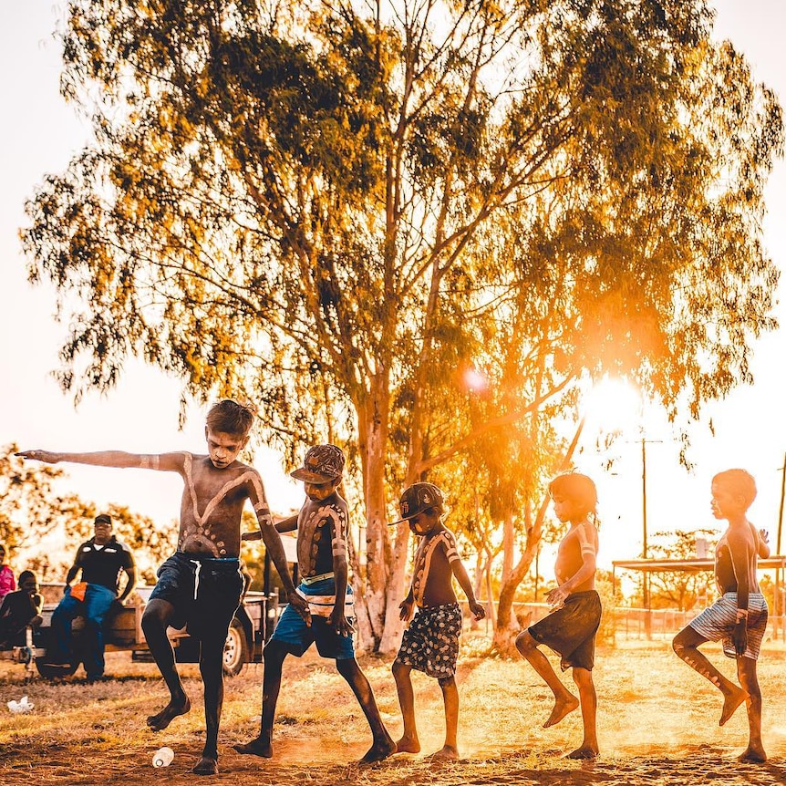 Young indigenous boys dance at sunset.
