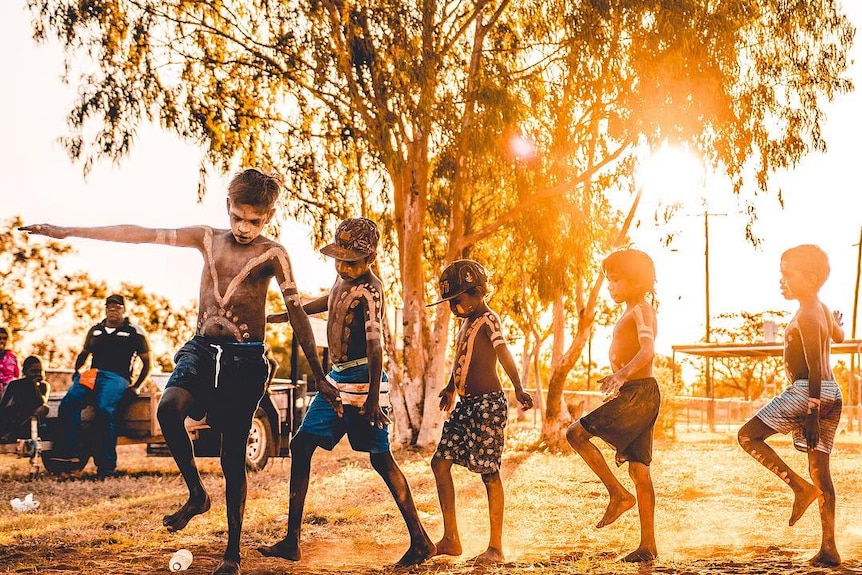 Jóvenes indígenas bailan al atardecer.