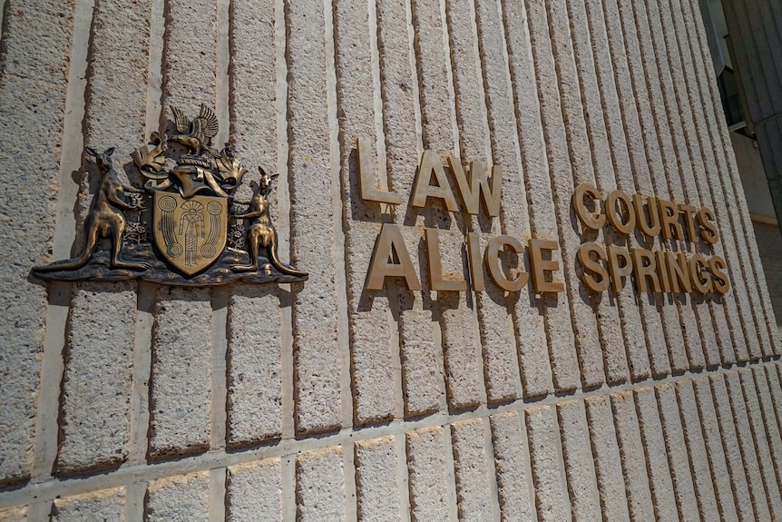 A sign reading 'Law Courts Alice Springs' on the wall of a building. 