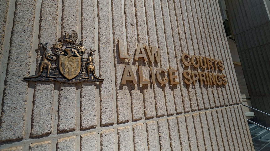A sign reading 'Law Courts Alice Springs' on the wall of a building. 