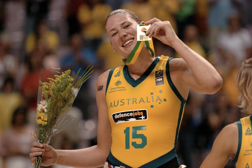 Lauren Jackson holds up a gold medal and smiles