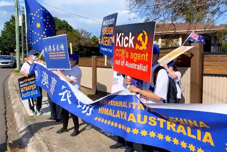 people on a suburban street holding anti chinese government signage