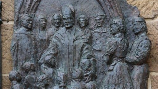 The bronze plaque depicts the former Monsignor with children