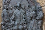 The bronze plaque depicts the former Monsignor with children