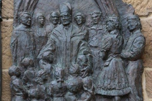 The bronze plaque depicts the former Monsignor with children