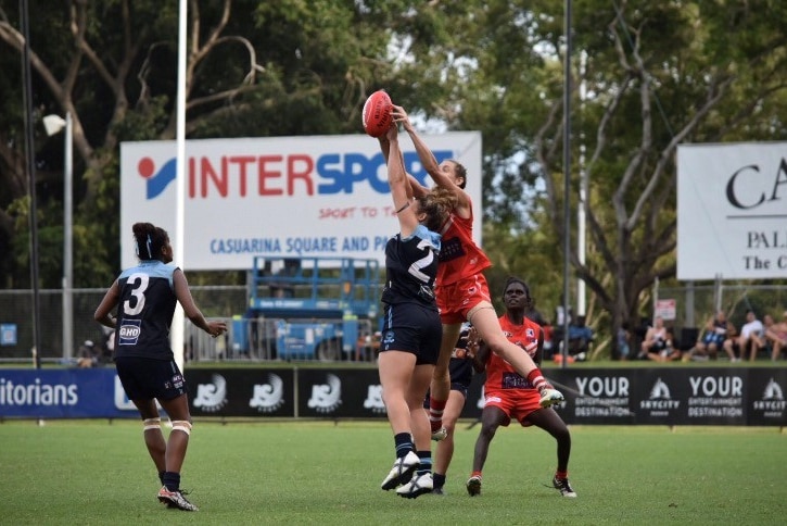 Two female football players jump for the ball in Darwin.