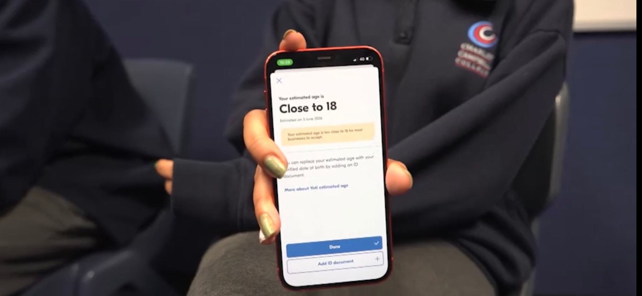 A student holds up a mobile phone that says "Close to 18".