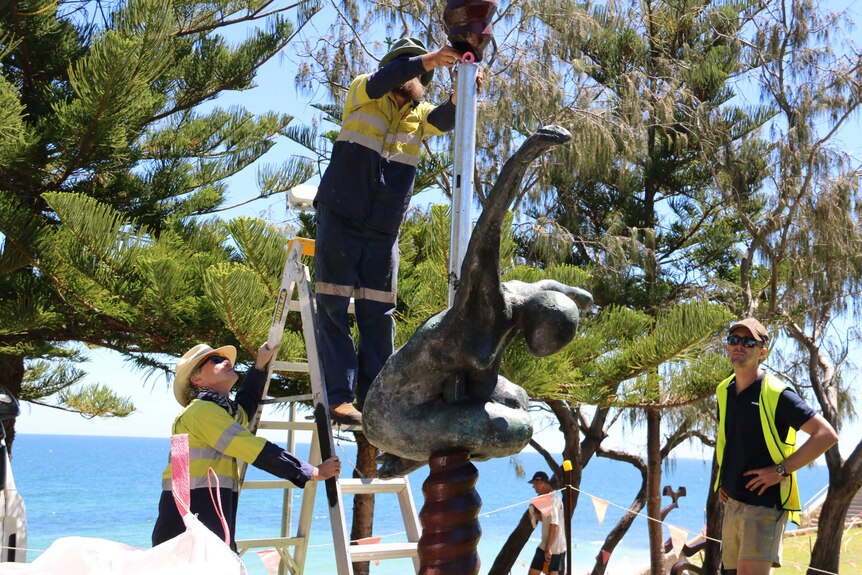 Toby Bell's 700 sculpture "The Cosmic Blacksmith" being erected at Cottesloe, with trees and the ocean in the background.