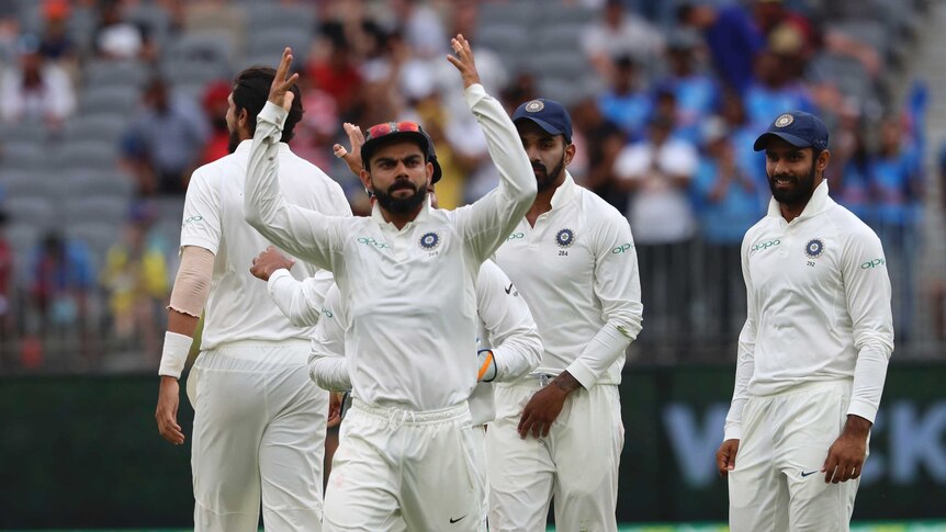 Virat Kohli throws his hands in the air, directing the crowd to get more animated during a cricket Test against Australia.