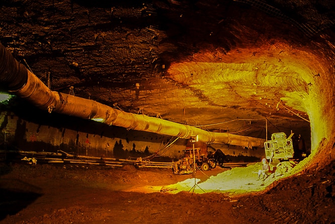 A man sits on a pile of rubble underground in a tunnel