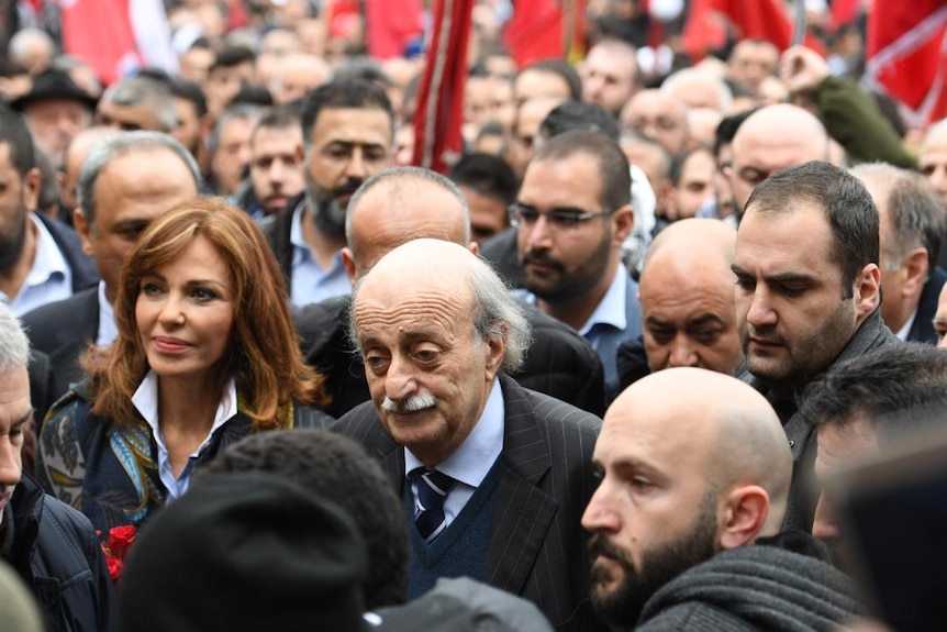 Walid Jumblatt walks in a crowd of supporters. He is bald and has a moustache.