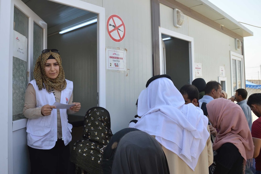 An Iraqi woman emerges from a demountable clinic, while others wait outside for their turn to go in.