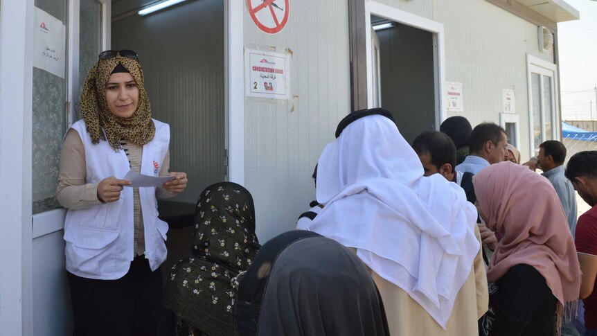 An Iraqi woman emerges from a demountable clinic, while others wait outside for their turn to go in.