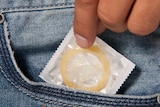 A condom is pulled from a jeans pocket.