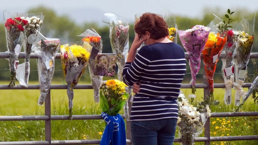 A woman looks at floral tributes where Garry Purdham was shot dead