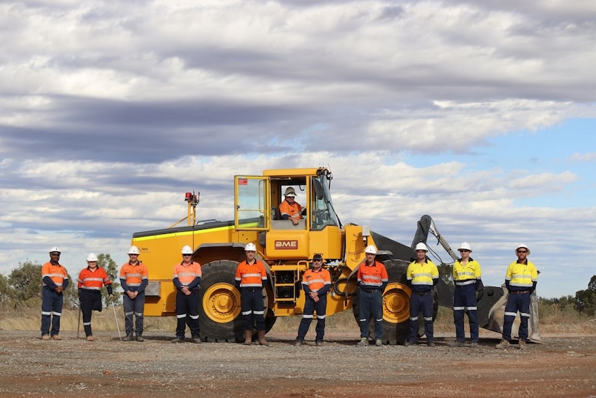 A big electric loader used in mining with staff standing in front.