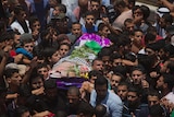 A group of mourners are seen carrying a body covered by the Palestinian flag and flower in a funeral procession.