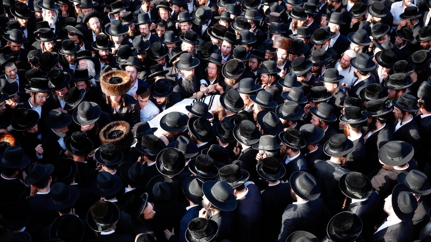  A large crowd of mourners dressed in black carry the body of a person who died in the stampede.