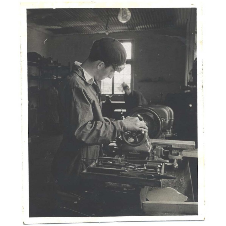 David Prince stands at a metal lathe in a workshop.