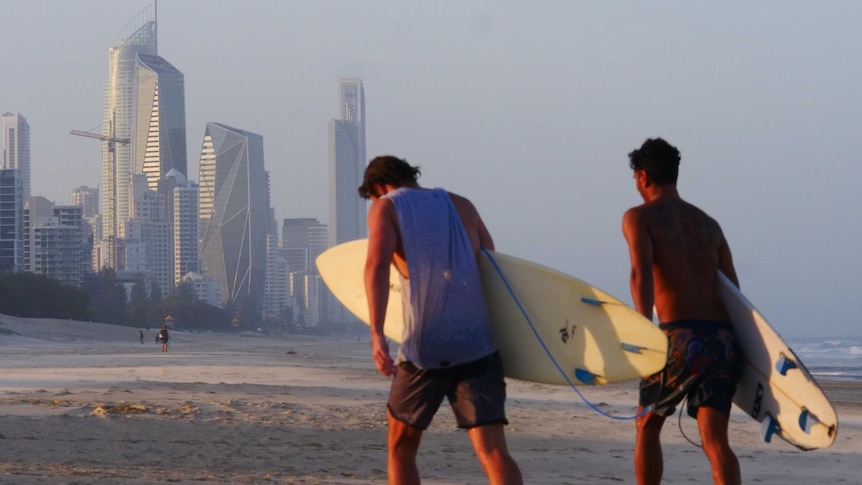 Two surfers with a city skyline in background