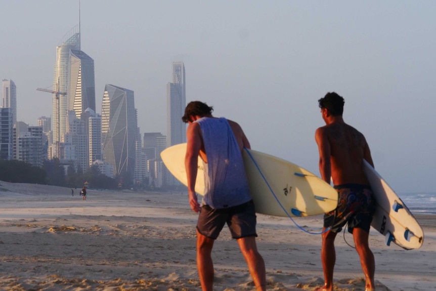 Two surfers, skyline in background