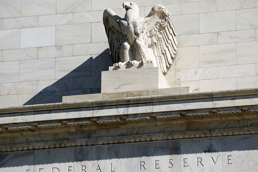 A close-up of an eagle sculpture and the words "Federal Reserve" engraved into the side of the building.